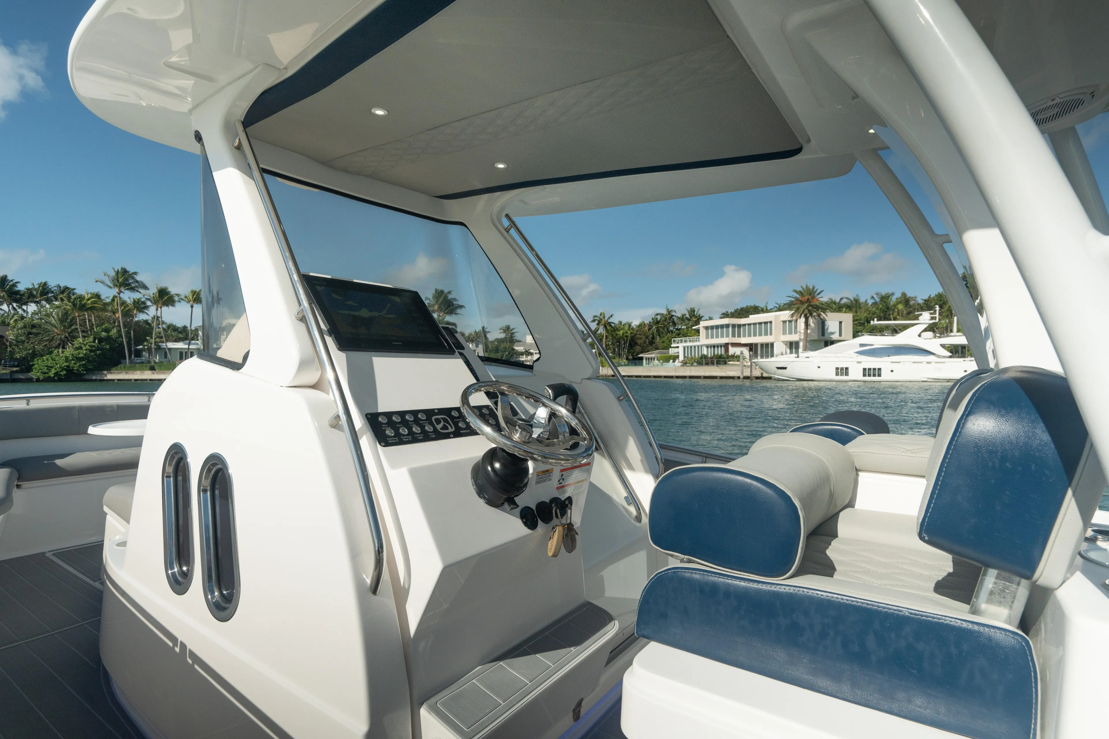  Yacht Photos Pics 2018 Belzona 325 Center Console boat interior with blue and white seating, docked near luxury homes.