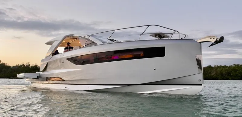  Yacht Photos Pics 2024 Jeanneau DB/43 OB luxury yacht cruising on calm waters at sunset.