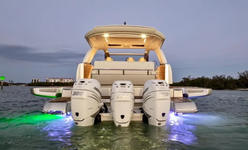  Yacht Photos Pics 2024 Jeanneau DB/43 OB boat with triple outboard engines, illuminated on water at dusk.