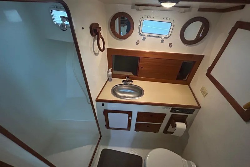  Yacht Photos Pics Compact bathroom in 1991 Holland 38 boat with sink, mirror, and shower.