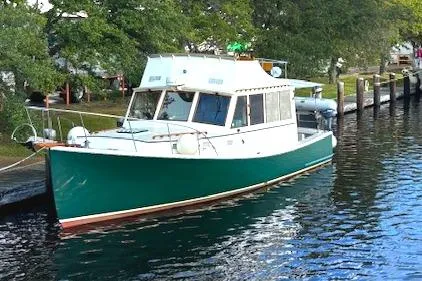  Yacht Photos Pics 1991 Holland 38 boat docked on calm water, surrounded by lush greenery.
