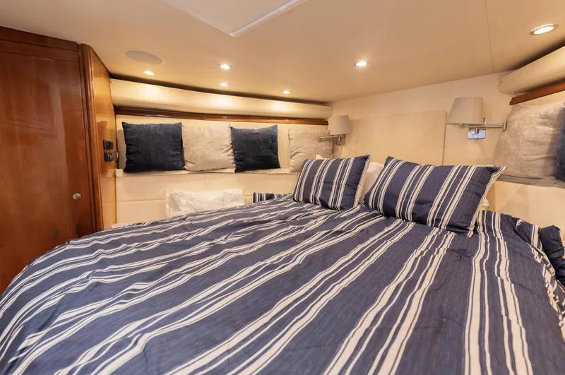  Yacht Photos Pics Luxurious bedroom interior of 2004 Bertram 630 yacht with striped bedding.