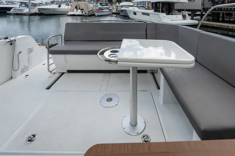Misty Step Yacht Photos Pics 2023 Beneteau Antares 11 boat deck with seating and table, docked at a marina.