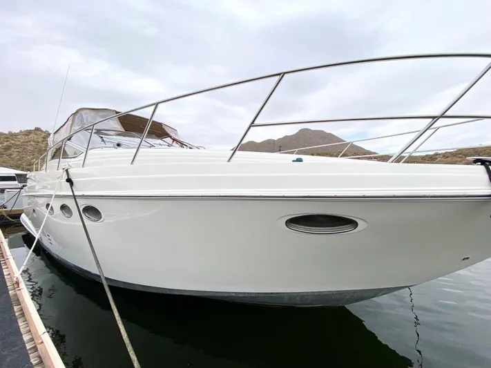Tangled Up In Blue Yacht Photos Pics 2002 Regal 3860 Commodore yacht docked on calm water, mountainous background.