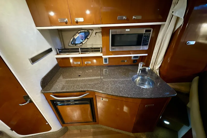  Yacht Photos Pics Luxurious 2012 Sea Ray 330 Sundancer yacht kitchen with microwave, sink, and wooden cabinetry.