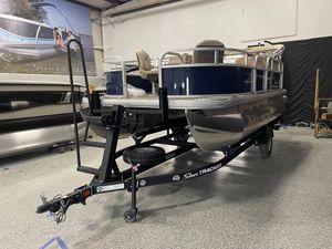 2025 Sun Tracker Bass Buggy 16 XL Select pontoon boat on trailer in showroom.