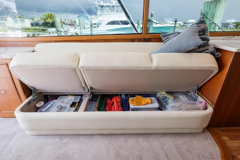 Double B Yacht Photos Pics Custom Carolina Taylor Made 2000 boat interior with storage under sofa, organized with various items.