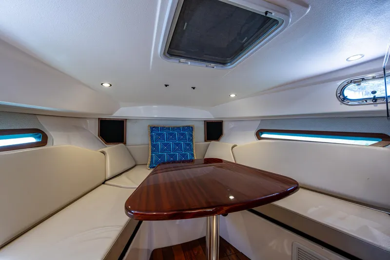 Cay Day Yacht Photos Pics 2017 Pursuit 325 OS cabin interior with seating and wooden table.