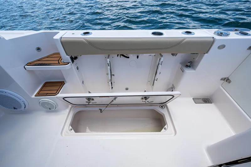 Cay Day Yacht Photos Pics 2017 Pursuit 325 OS boat interior with storage compartment and seating, on calm water.