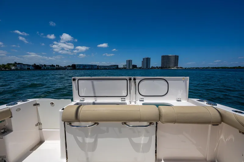 Cay Day Yacht Photos Pics 2017 Pursuit 325 OS boat with beige seating, ocean view, and city skyline in the background.