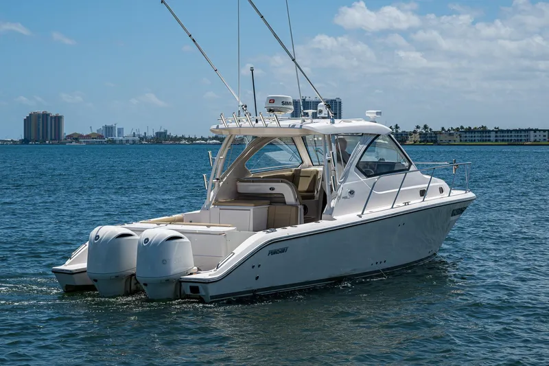 Cay Day Yacht Photos Pics 2017 Pursuit 325 OS boat on water, clear sky, city skyline in background.
