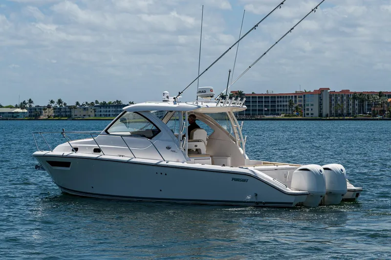 Cay Day Yacht Photos Pics 2017 Pursuit 325 OS boat on water with fishing rods, cityscape in background.