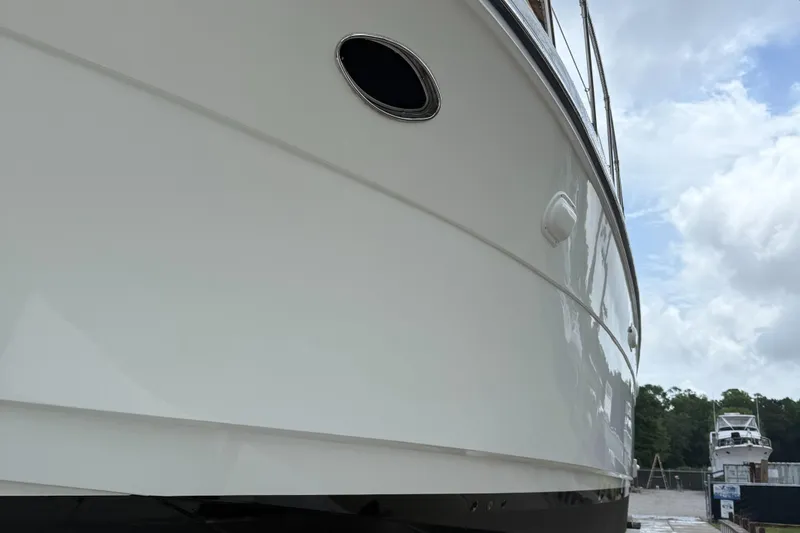 Adagio Yacht Photos Pics 2005 Jefferson Rivanna 50 SDMY yacht hull, close-up view with cloudy sky background.