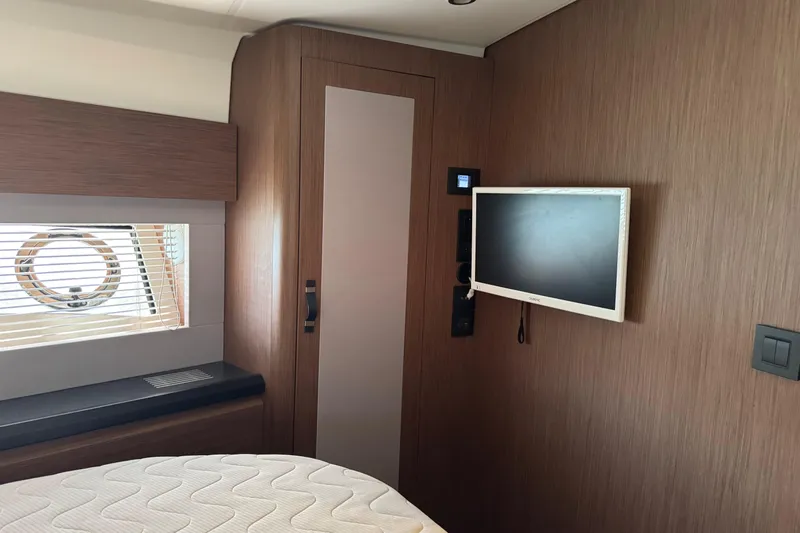  Yacht Photos Pics Interior of 2020 Monte Carlo 52 yacht with TV, window, and wooden paneling.