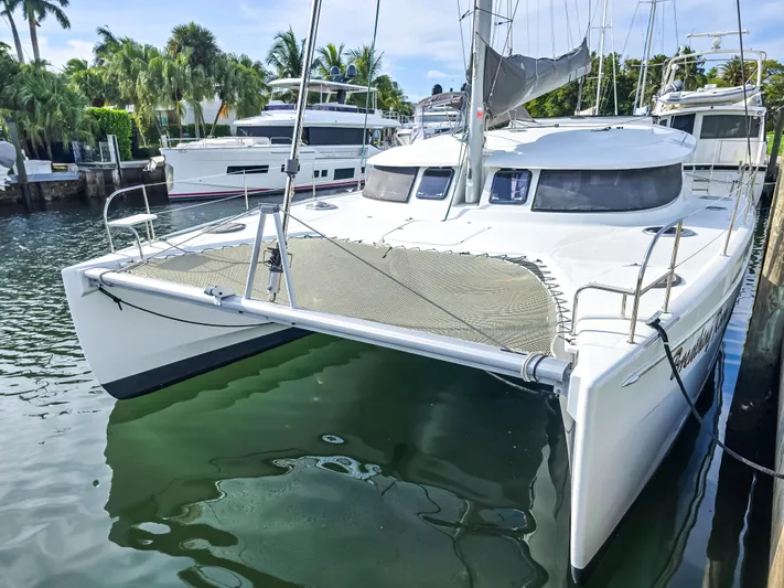 Breathing Room Yacht Photos Pics 2014 Fountaine Pajot Lipari 41 catamaran docked, surrounded by palm trees and calm water.