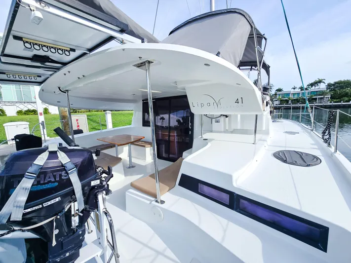 Breathing Room Yacht Photos Pics 2014 Fountaine Pajot Lipari 41 catamaran with outdoor seating and motor, docked by waterfront homes.