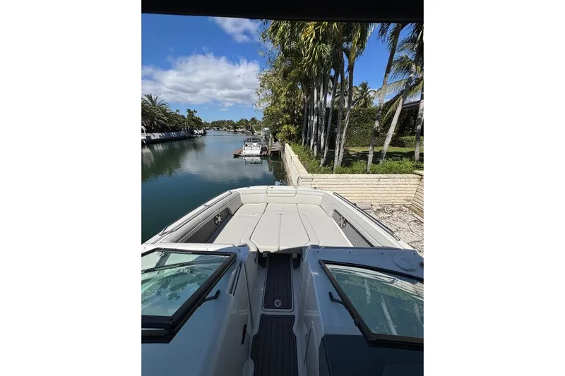  Yacht Photos Pics 2025 Sea Ray SDX 290 Outboard boat docked by a scenic canal with palm trees.
