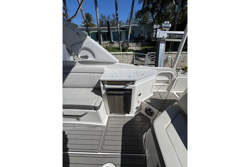  Yacht Photos Pics 2025 Sea Ray SDX 290 Outboard interior with seating and kitchenette, docked near palm trees.
