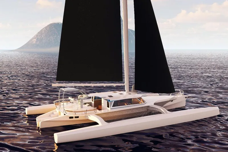  Yacht Photos Pics 2026 Rapido 63 trimaran sailing on calm ocean with distant island backdrop.