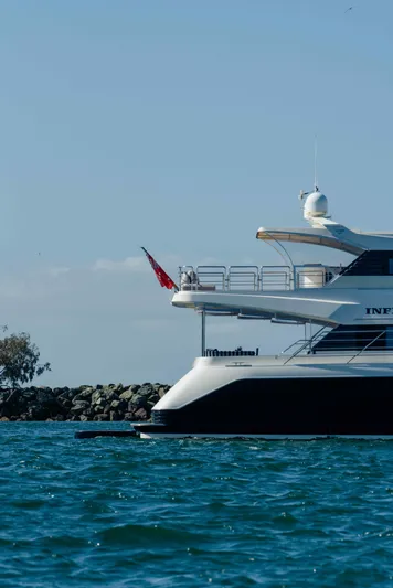 Infinite Yacht Photos Pics Warren Yachts 85 Motor Yacht, 1999 model, cruising on blue waters near rocky shoreline.