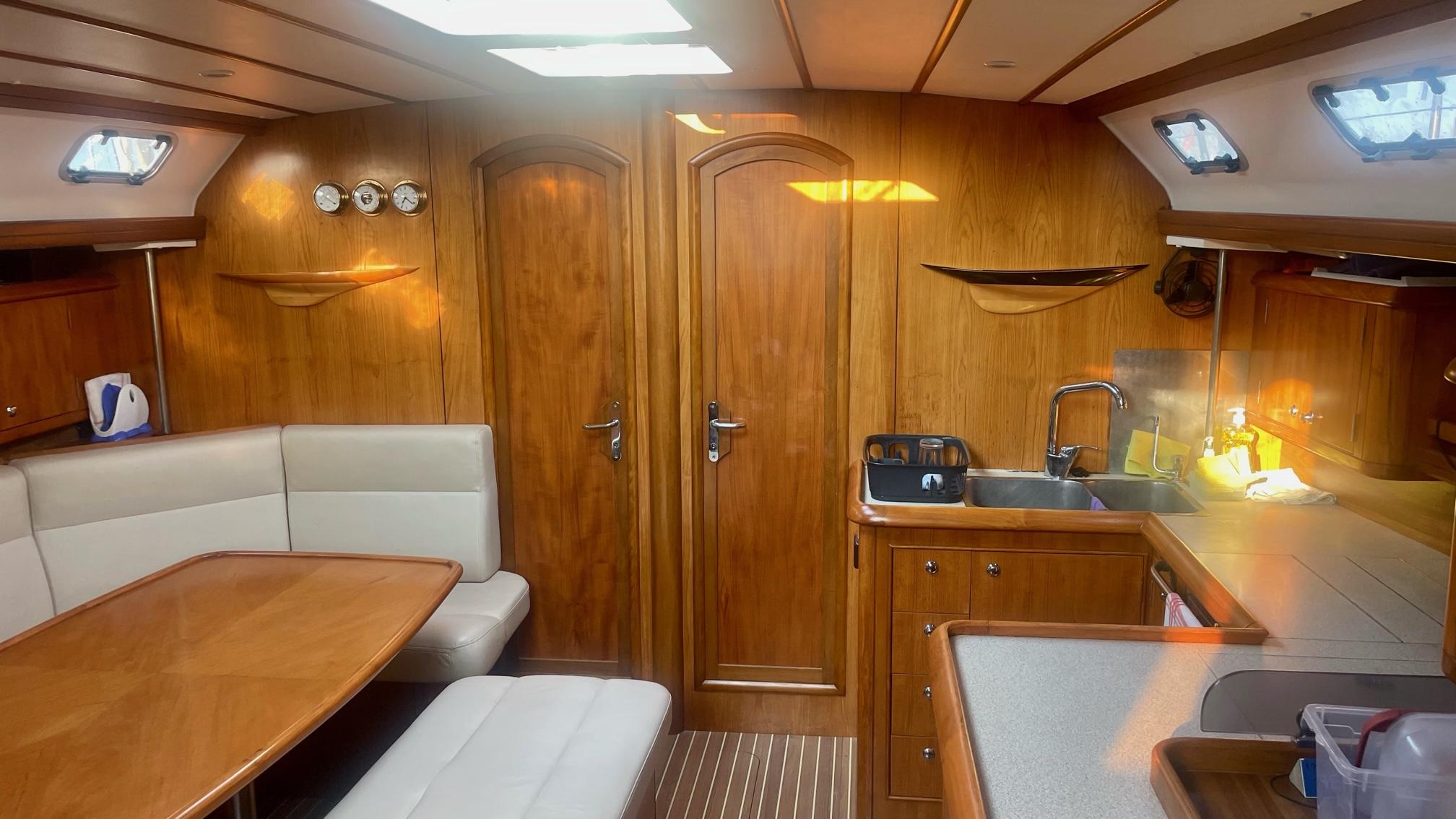 Luxurious 2003 Alpha 51 yacht interior with wooden finish, dining area, and kitchenette.