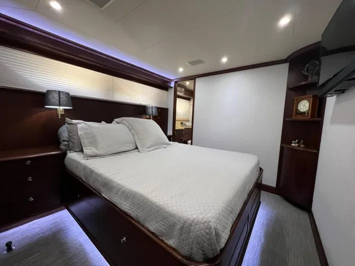 Lucky Again Yacht Photos Pics Luxurious bedroom in a 2005 Pacific Mariner 85 yacht, featuring elegant wood finishes and ambient lighting.
