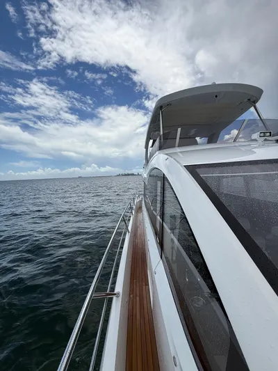 4 Play Yacht Photos Pics 2022 Sunseeker Manhattan 68 yacht cruising on open water under a partly cloudy sky.