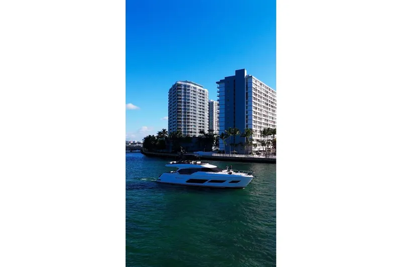  Yacht Photos Pics 2023 Ferretti Yachts 720 cruising near modern waterfront buildings.