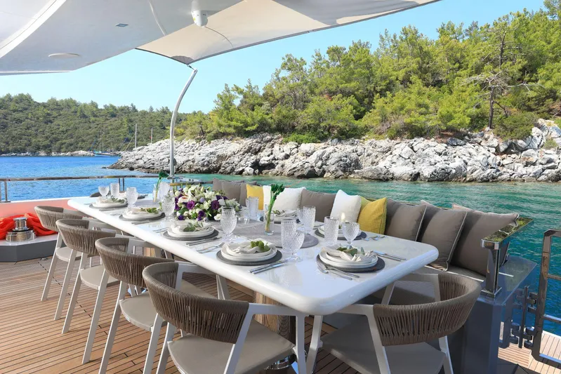 Tortura Yacht Photos Pics Luxurious dining setup on Aegean Explorer yacht, 2025, with scenic ocean and forest backdrop.