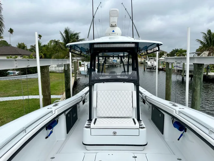  Yacht Photos Pics 2024 Yellowfin 36 boat with white seating and fishing rods, docked in a marina.