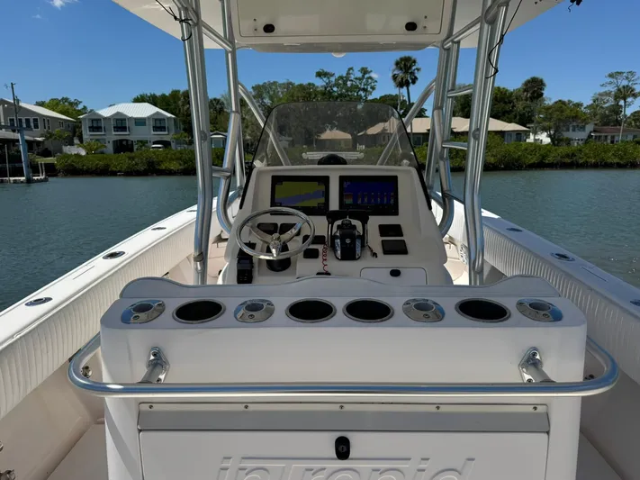  Yacht Photos Pics 2006 Intrepid 323 boat cockpit with steering wheel, navigation screens, and rod holders on a sunny day.