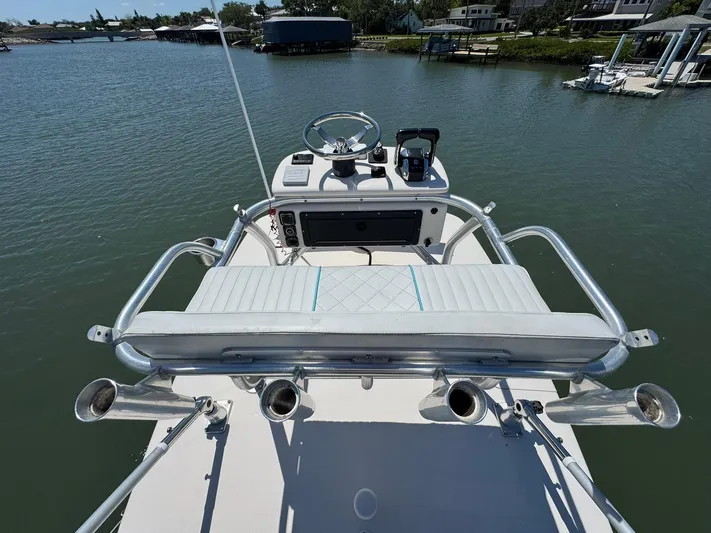  Yacht Photos Pics 2006 Intrepid 323 boat helm with steering wheel, controls, and rod holders on a calm waterway.