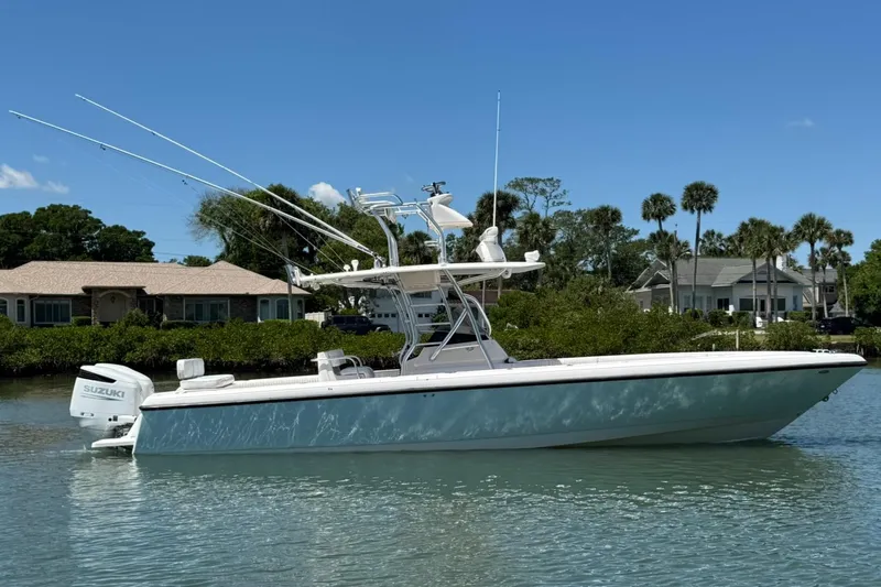  Yacht Photos Pics 2006 Intrepid 323 boat with Suzuki engine on calm water, surrounded by greenery and houses.