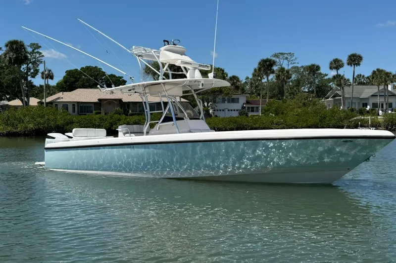  Yacht Photos Pics 2006 Intrepid 323 boat on calm water, surrounded by lush greenery and residential homes.
