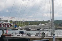 Docked 1989 Custom Scandinavian Cruiser Eagle sailboat with folded sails, surrounded by flags and waterfront buildings.