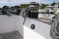 Sailboat deck with ropes, Scandinavian Cruiser Eagle, 1989, docked near lush greenery.