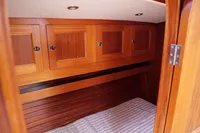 Wooden cabin interior of 1989 Scandinavian Cruiser Eagle, featuring storage cabinets and a striped bed.