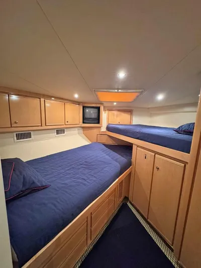  Yacht Photos Pics Cozy cabin interior of 1999 Bertram 60 Convertible yacht with twin beds and wooden cabinetry.