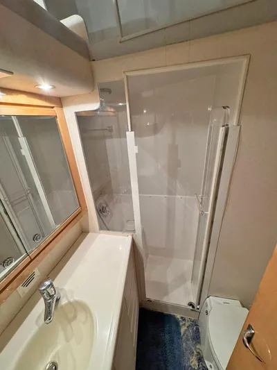  Yacht Photos Pics Bathroom interior of a 1999 Bertram 60 Convertible yacht, featuring a shower and sink.