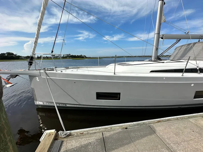Chasing Summer Yacht Photos Pics 2022 Beneteau Oceanis 46.1 sailboat docked by a serene waterfront.