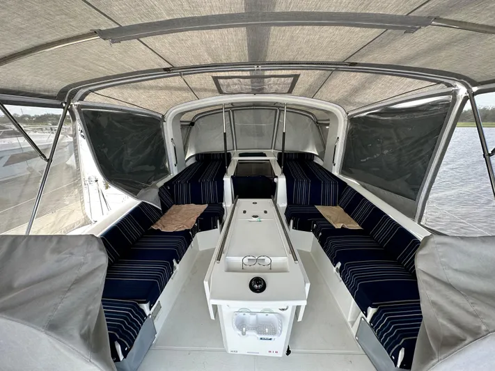 Chasing Summer Yacht Photos Pics Interior view of 2022 Beneteau Oceanis 46.1 sailboat with striped seating and covered deck.
