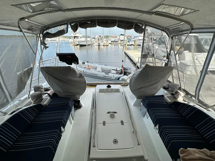 Chasing Summer Yacht Photos Pics Interior view of 2022 Beneteau Oceanis 46.1 yacht at marina, featuring seating and covered helm.