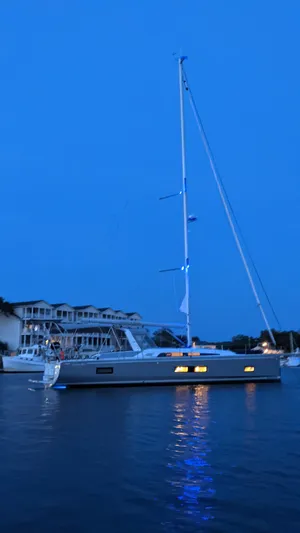 Chasing Summer Yacht Photos Pics 2022 Beneteau Oceanis 46.1 sailboat illuminated at dusk on calm waters.