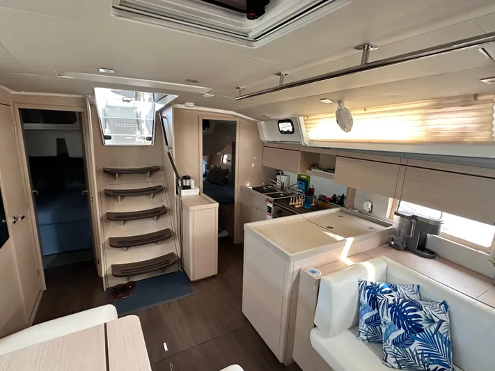 Chasing Summer Yacht Photos Pics Luxurious interior of 2022 Beneteau Oceanis 46.1 yacht with modern kitchen and seating area.