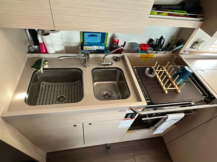 Chasing Summer Yacht Photos Pics Modern kitchen area in a 2022 Beneteau Oceanis 46.1 yacht, featuring dual sinks and storage.