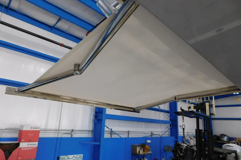 Three Point O.h. Yacht Photos Pics 2022 Pursuit S 328 Sport boat with extended sunshade in a blue indoor facility.