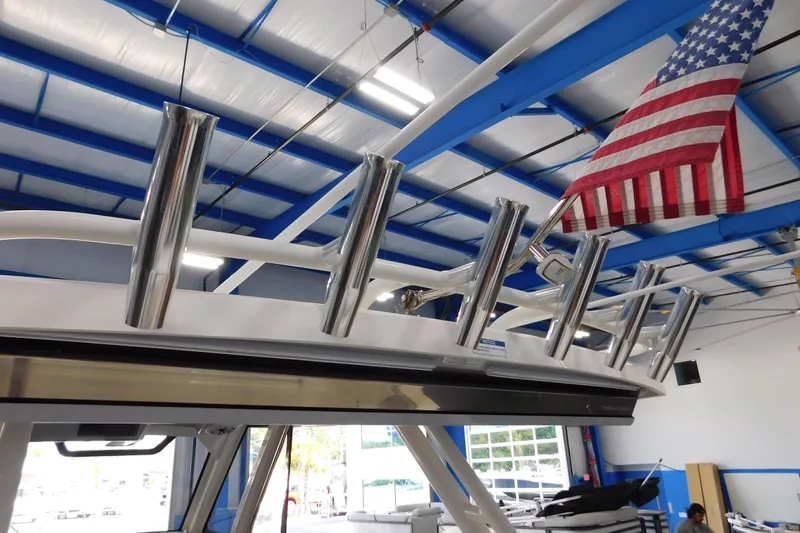 Three Point O.h. Yacht Photos Pics 2022 Pursuit S 328 Sport boat with rod holders and American flag in a showroom.