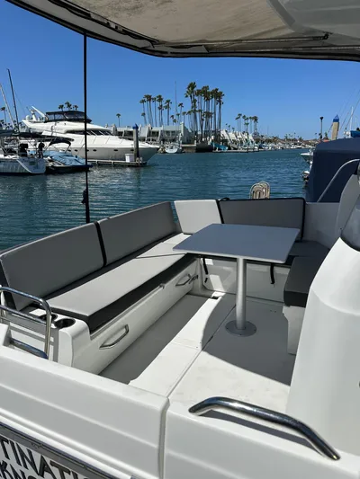 Destination Unknown II Yacht Photos Pics 2021 Jeanneau NC 895 boat with seating area, docked in a marina with palm trees.