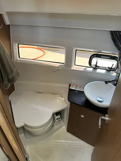Destination Unknown II Yacht Photos Pics 2021 Jeanneau NC 895 boat bathroom with toilet, sink, and windows.
