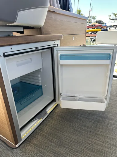 Destination Unknown II Yacht Photos Pics 2021 Jeanneau NC 895 boat interior with open mini fridge, showcasing storage space.